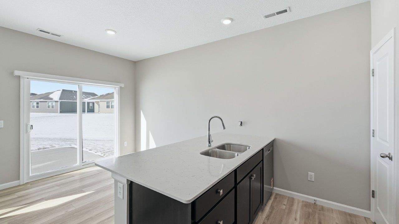 kitchen with sarsaparilla shaker cabinets, quartz counters, stainless steel appliances, ceramic tile backsplash, and island with seating