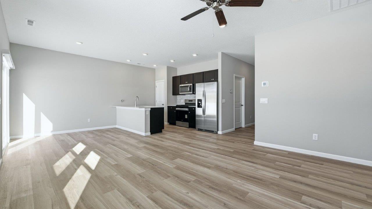 open layout living room, kitchen, and dining room with lvp flooring and popular grey walls