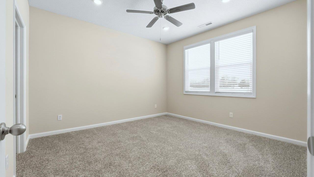 primary bedroom with carpet, fan, and ensuite bath and closet
