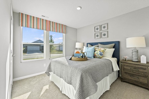 Timber Creek Chatham Model Home - Bedroom 2 with 2 windows and carpet flooring.