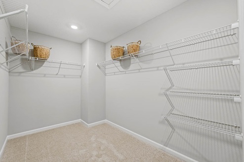 Timber Creek Chatham Model Home - Walk in closet off of the main bedroom with carpet flooring and wire shelving.