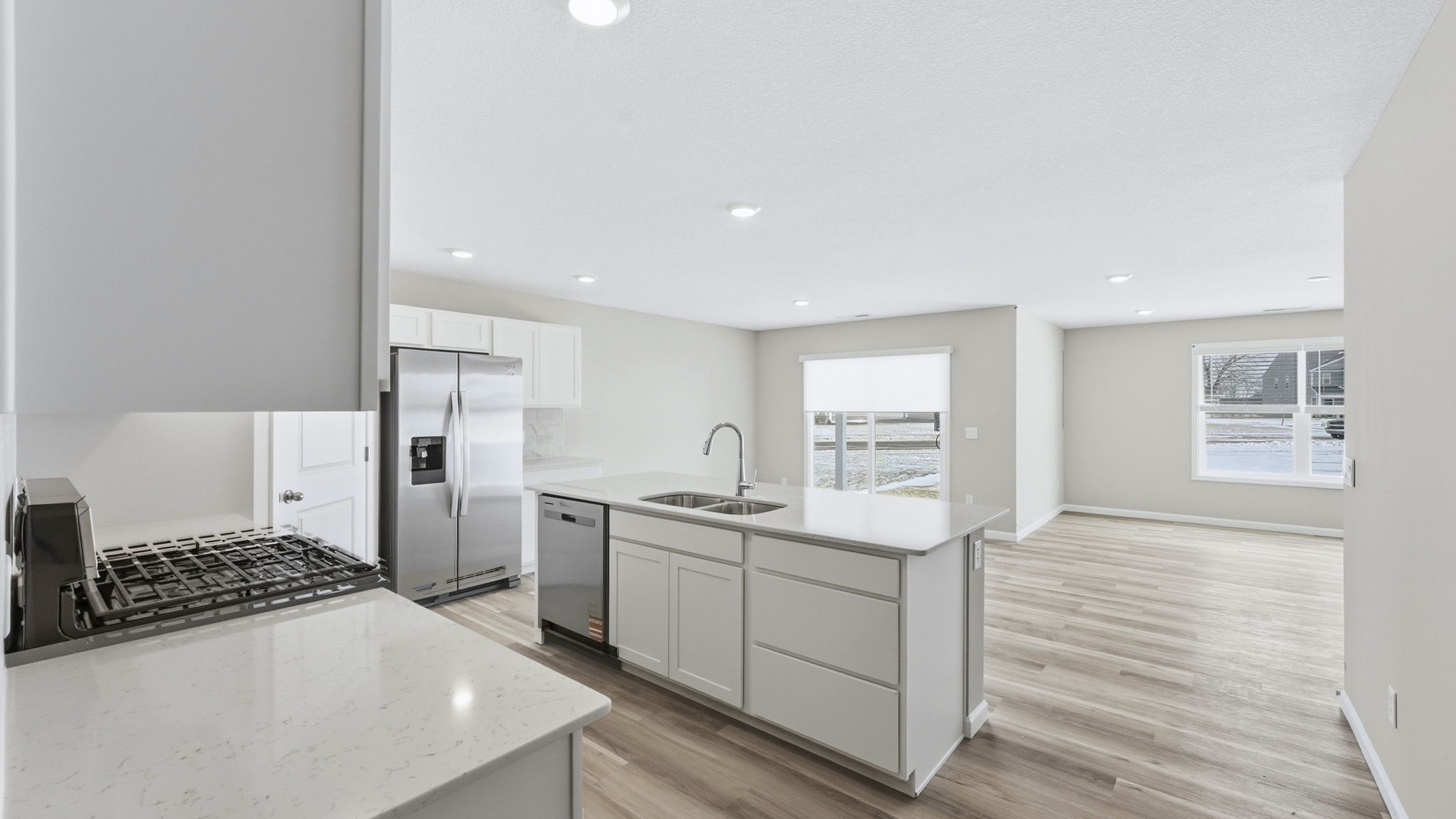 kitchen with white cabinets, tile backsplash, quartz counters, appliances, center island with bar seating, and corner pantry
