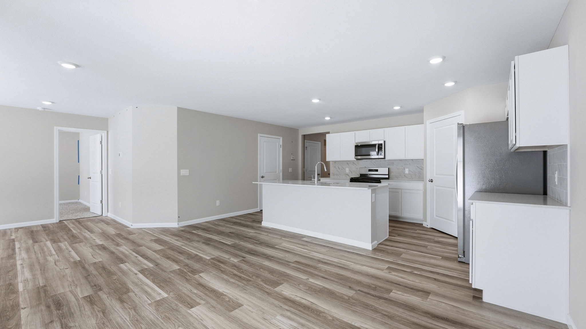 kitchen with white cabinets, tile backsplash, quartz counters, appliances, center island with bar seating, and corner pantry