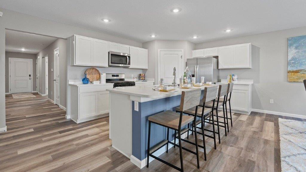 Chatham kitchen with stainless steel appliances, large island with seating, quartz counters, lvp flooring, and pantry