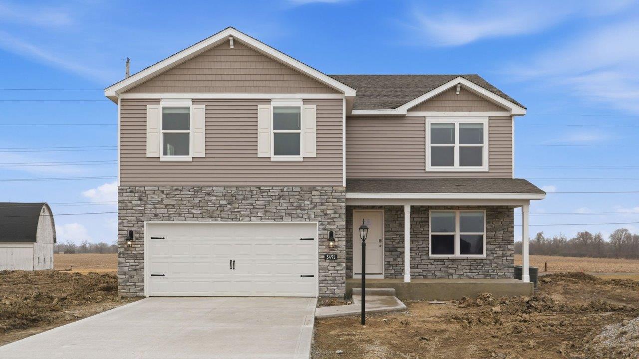 fawn creek estates henley with 2 car garage, large homesite, front covered patio with moonlit trail stone, heather shake, white shutters, and heather vinyl siding