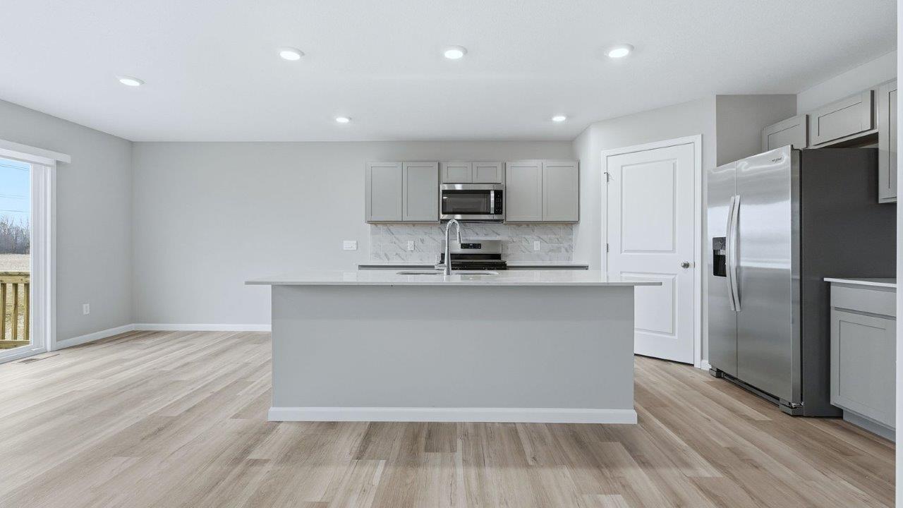 kitchen with grey cabinets, stainless steel appliances, corner pantry, ceramic tile backsplash, and quartz countertops
