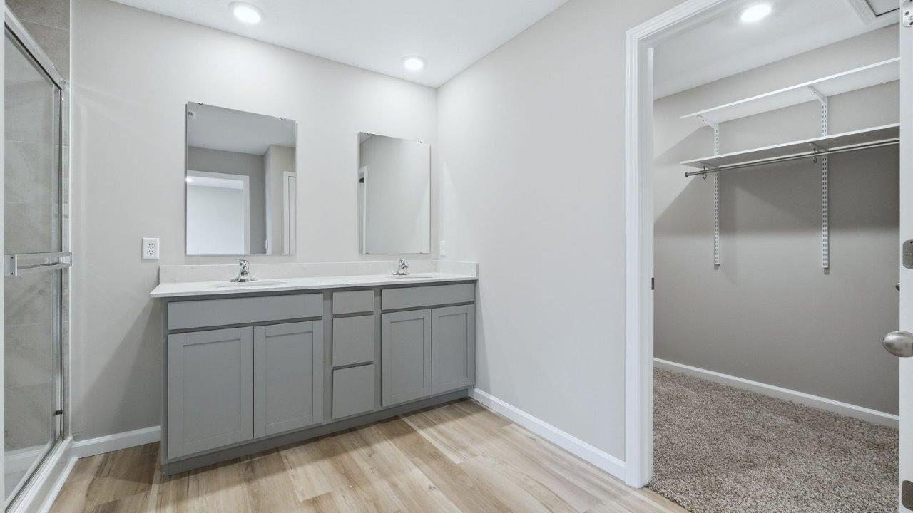 primary bedroom ensuite bathroom with dual sinks, walk-in shower, linen closet, and private water room