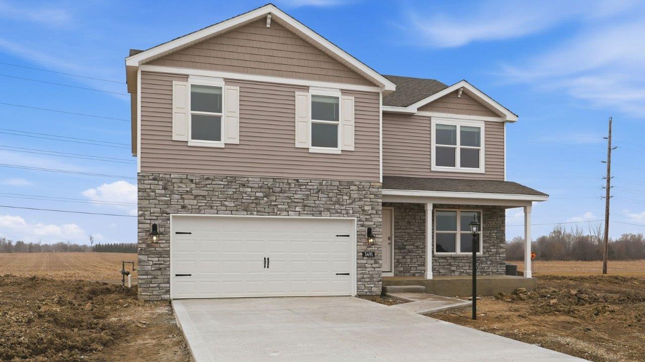 fawn creek estates henley with 2 car garage, large homesite, front covered patio with moonlit trail stone, heather shake, white shutters, and heather vinyl siding