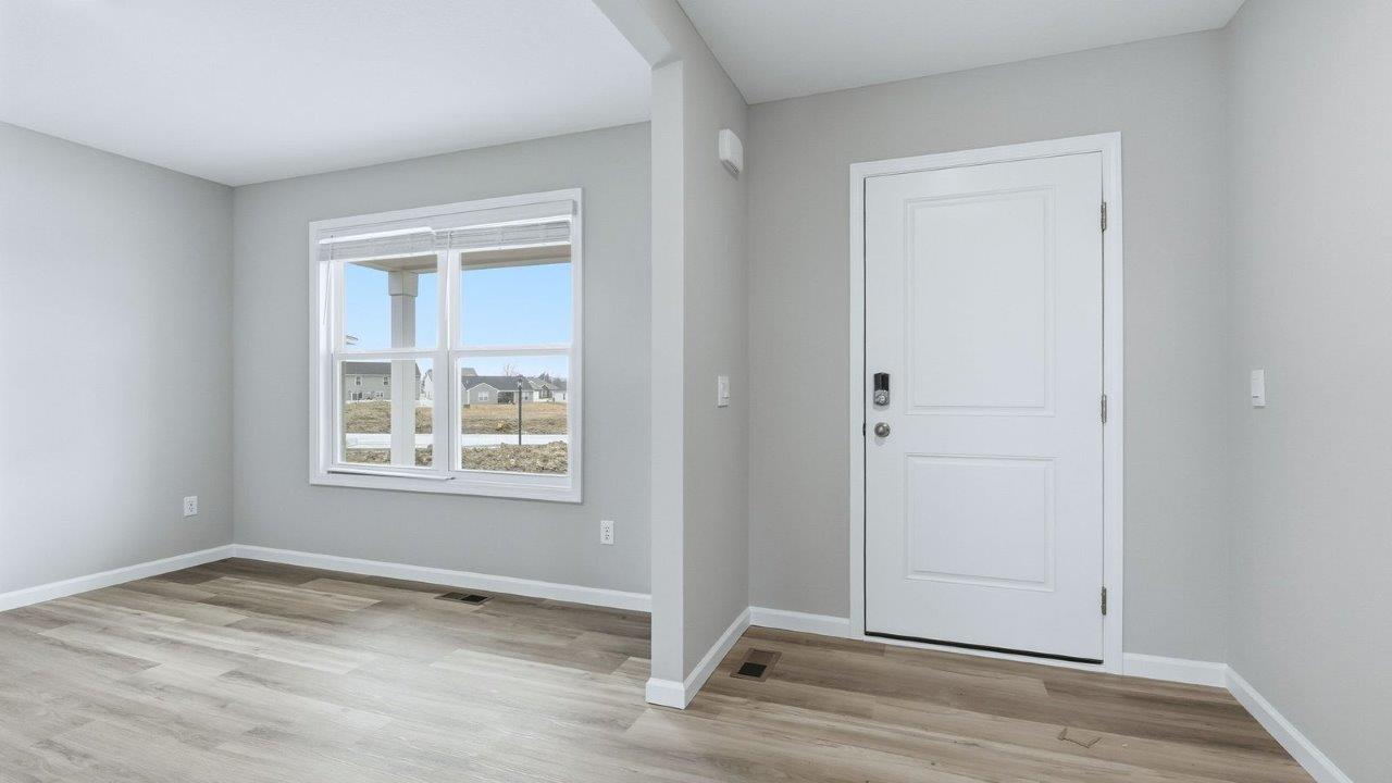 front door and foyer with mohawk avery lvp flooring and popular grey walls opening to study and main living area