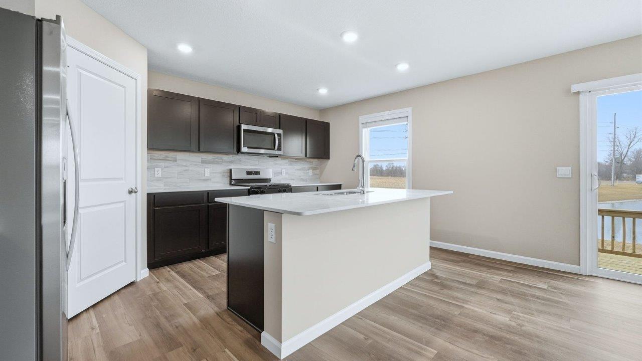 kitchen with sarsaparilla cabinets, stainless steel appliances, quartz countertops, and center island with bar seating