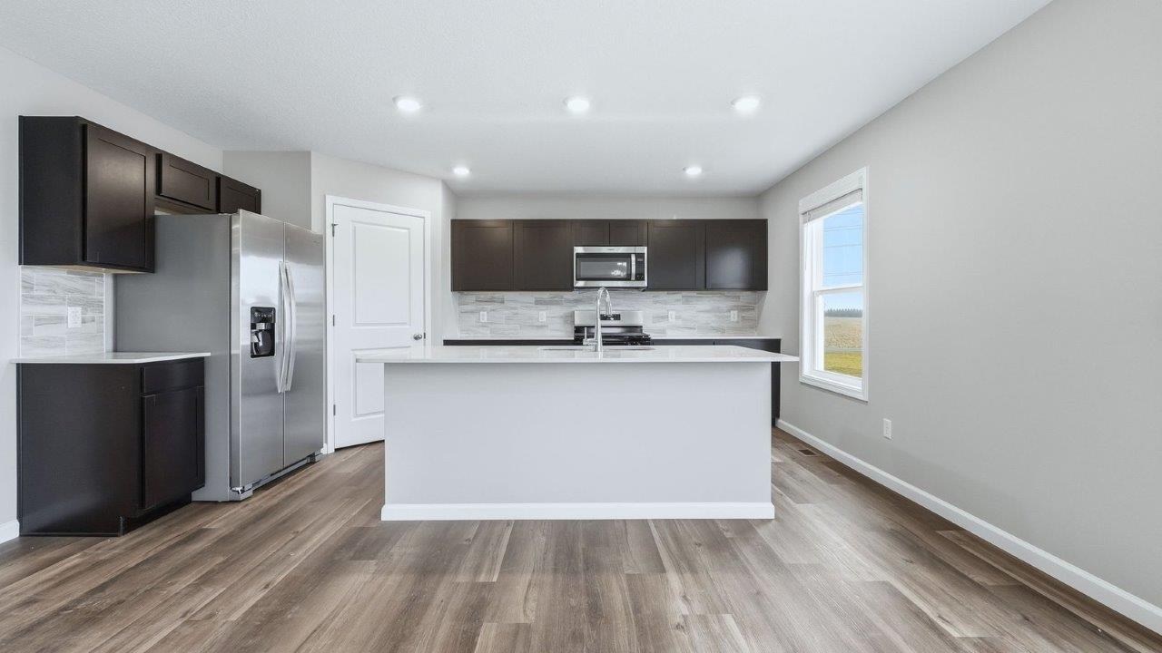 kitchen with sarsaparilla cabinets, stainless steel appliances, quartz countertops, and center island with bar seating
