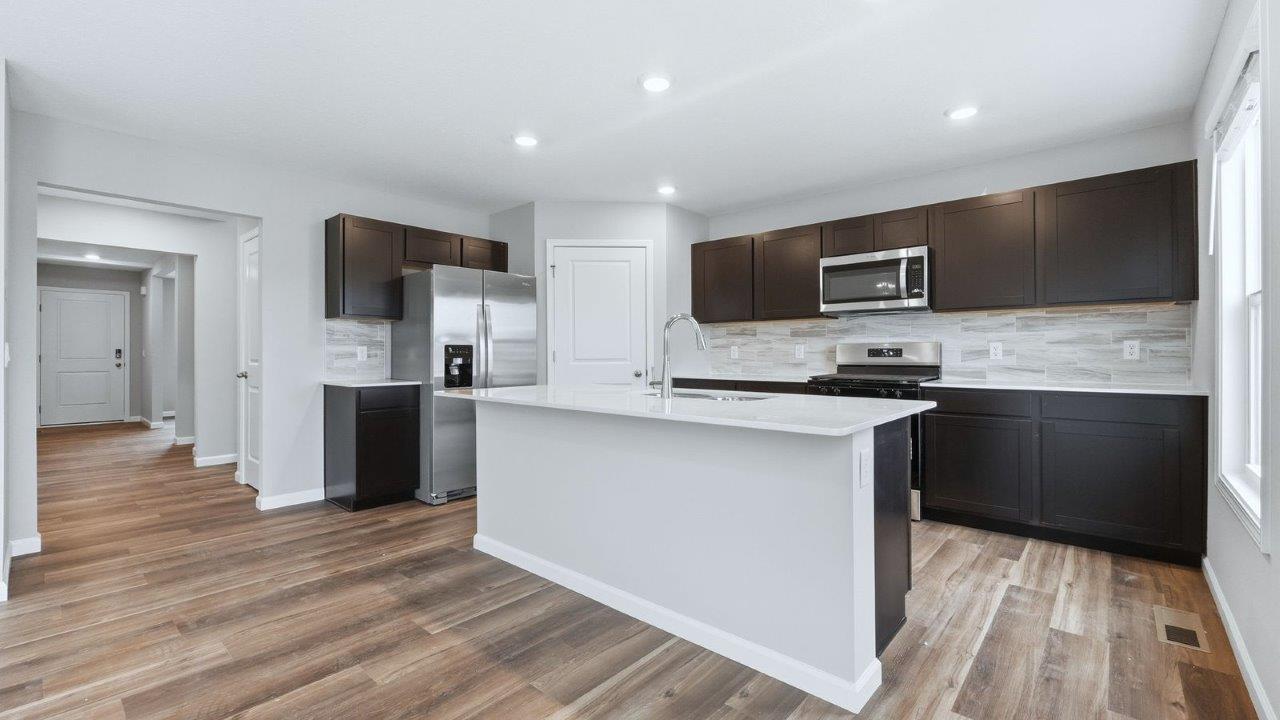 kitchen with sarsaparilla cabinets, stainless steel appliances, quartz countertops, and center island with bar seating