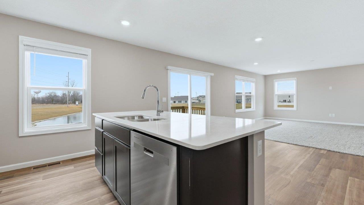 kitchen with sarsaparilla cabinets, stainless steel appliances, quartz countertops, and center island with bar seating