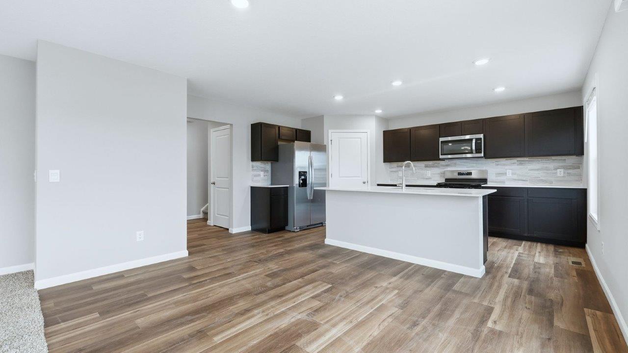 kitchen with sarsaparilla cabinets, stainless steel appliances, quartz countertops, and center island with bar seating