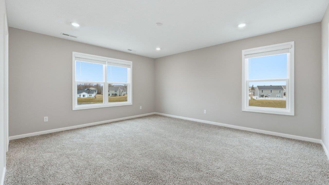 primary bedroom with 3 windows, carpet, and ensuite bath and closet