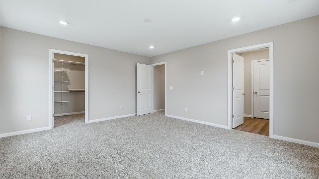 primary bedroom with 3 windows, carpet, and ensuite bath and closet