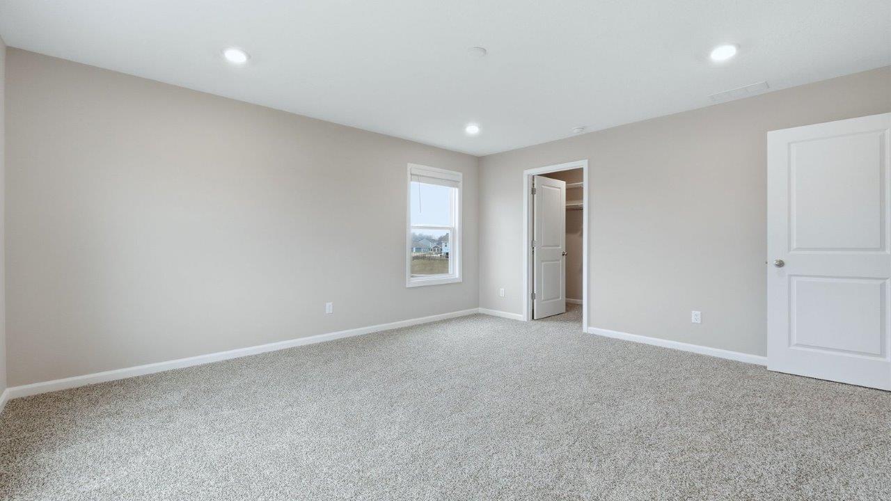 primary bedroom with 3 windows, carpet, and ensuite bath and closet