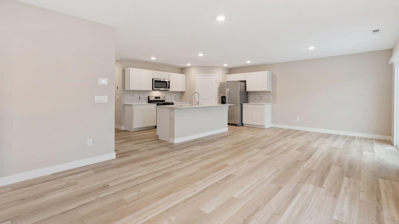 fawn creek estates freeport - open layout living room with mohawk lvp flooring, 2 windows, and open to kitchen and dining room