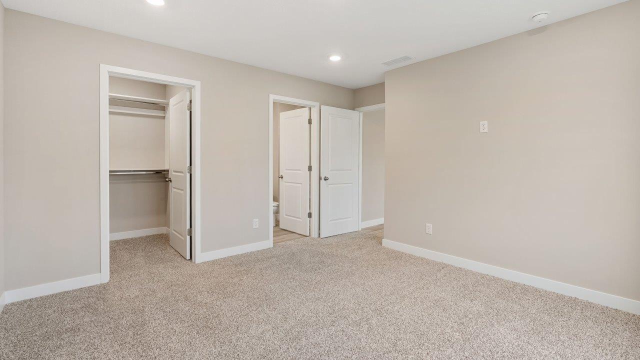 fawn creek estates freeport - primary bedroom with carpet flooring, 2 windows, and ensuite bathroom and walk in closet