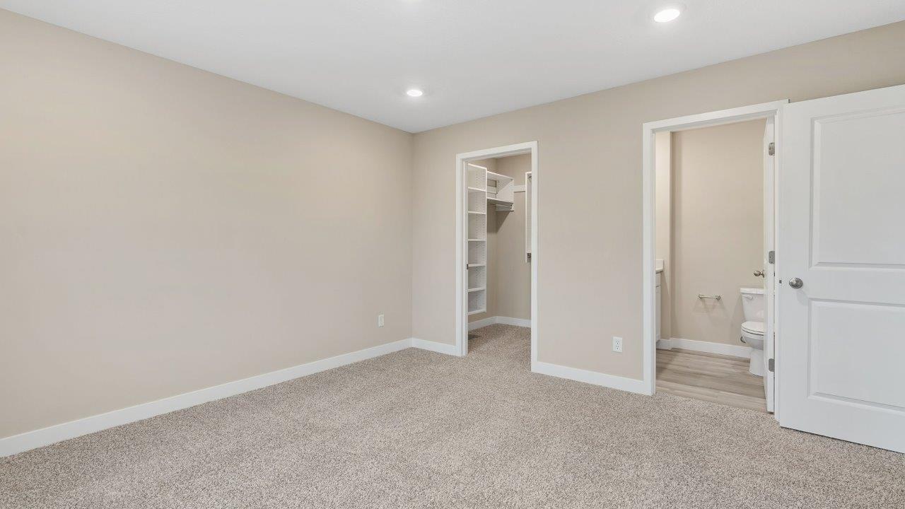 fawn creek estates freeport - primary bedroom with carpet flooring, 2 windows, and ensuite bathroom and walk in closet