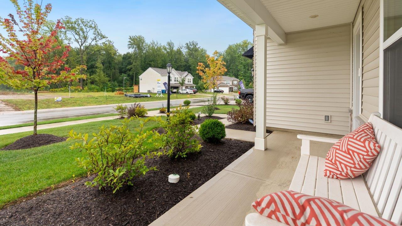 farmstead at carroll creek henley model home exterior with covered front porch, sodded yard, and landscaping