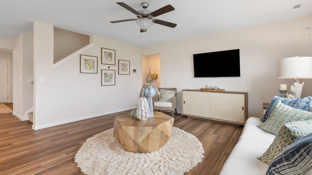 farmstead at carroll creek henley model home open layout living room with mohawk eastmont lvp, ceiling fan, 2 windows, and heron plume painted walls