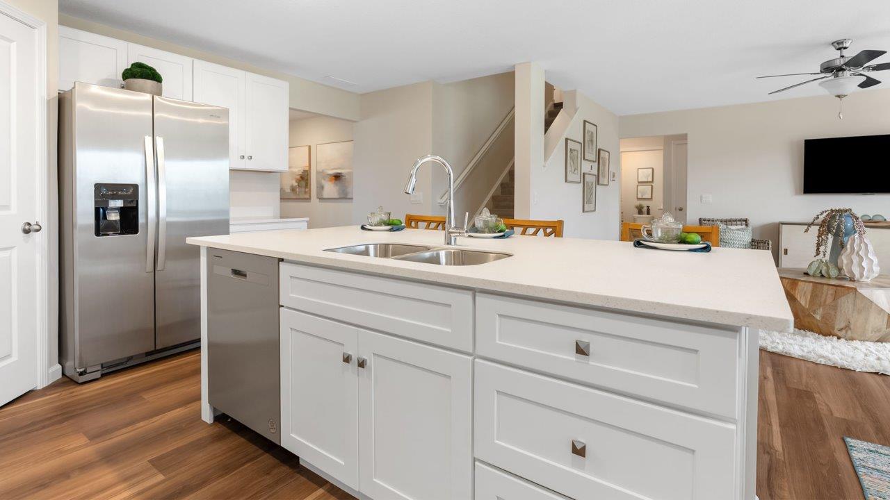 farmstead at carroll creek henley model home kitchen with white shaker cabinets, island with seating, pantry, stainless steel appliances, and quartz countertops