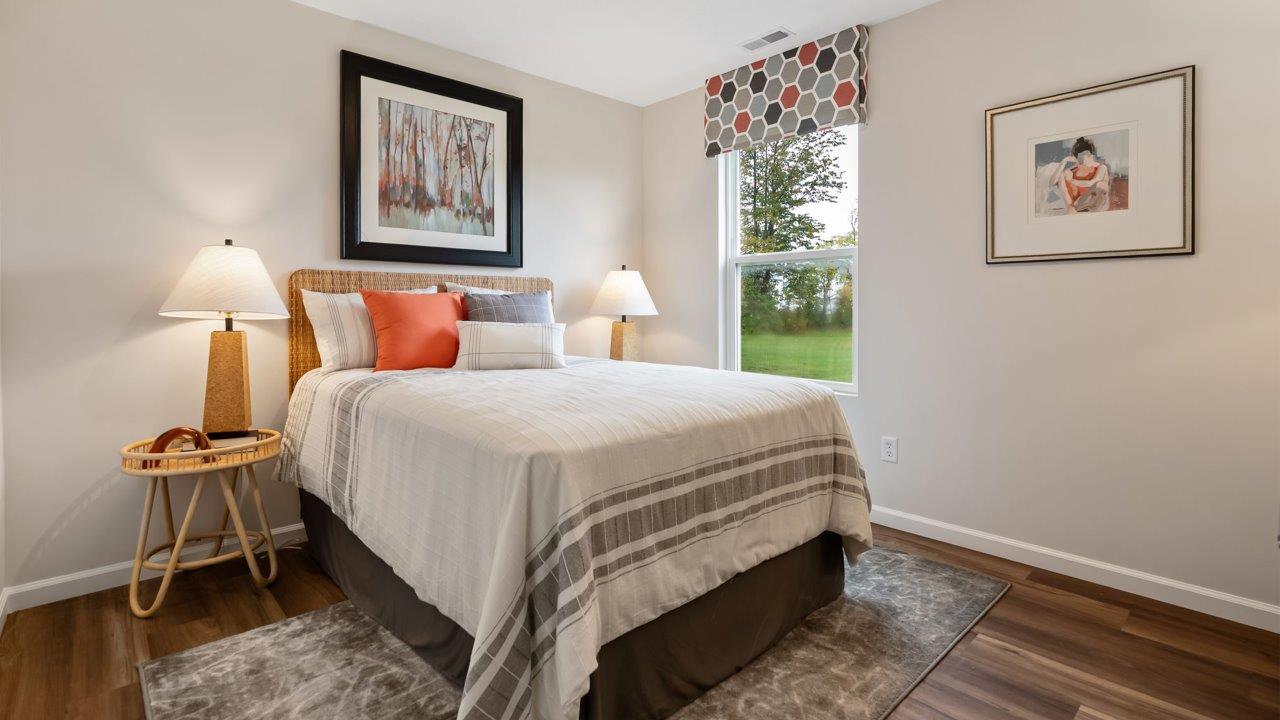 farmstead at carroll creek henley model home first floor bedroom with lvp flooring, single window, heron plume walls, and nearby full guest bathroom