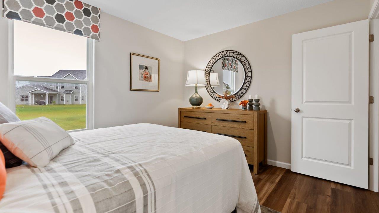 farmstead at carroll creek henley model home first floor bedroom with lvp flooring, single window, heron plume walls, and nearby full guest bathroom