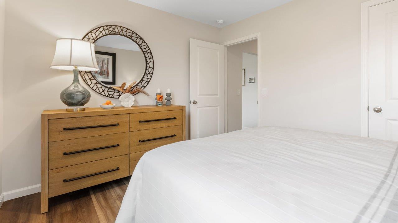 farmstead at carroll creek henley model home first floor bedroom with lvp flooring, single window, heron plume walls, and nearby full guest bathroom