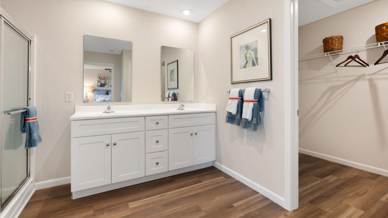 farmstead at carroll creek henley model home primary ensuite bathroom with dual sink vanity, lvp flooring, walk in shower
