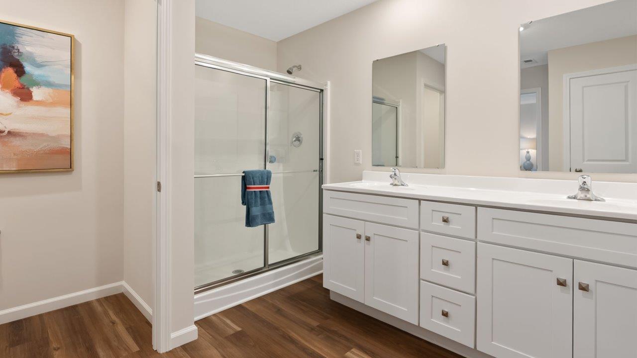 farmstead at carroll creek henley model home primary ensuite bathroom with dual sink vanity, lvp flooring, walk in shower