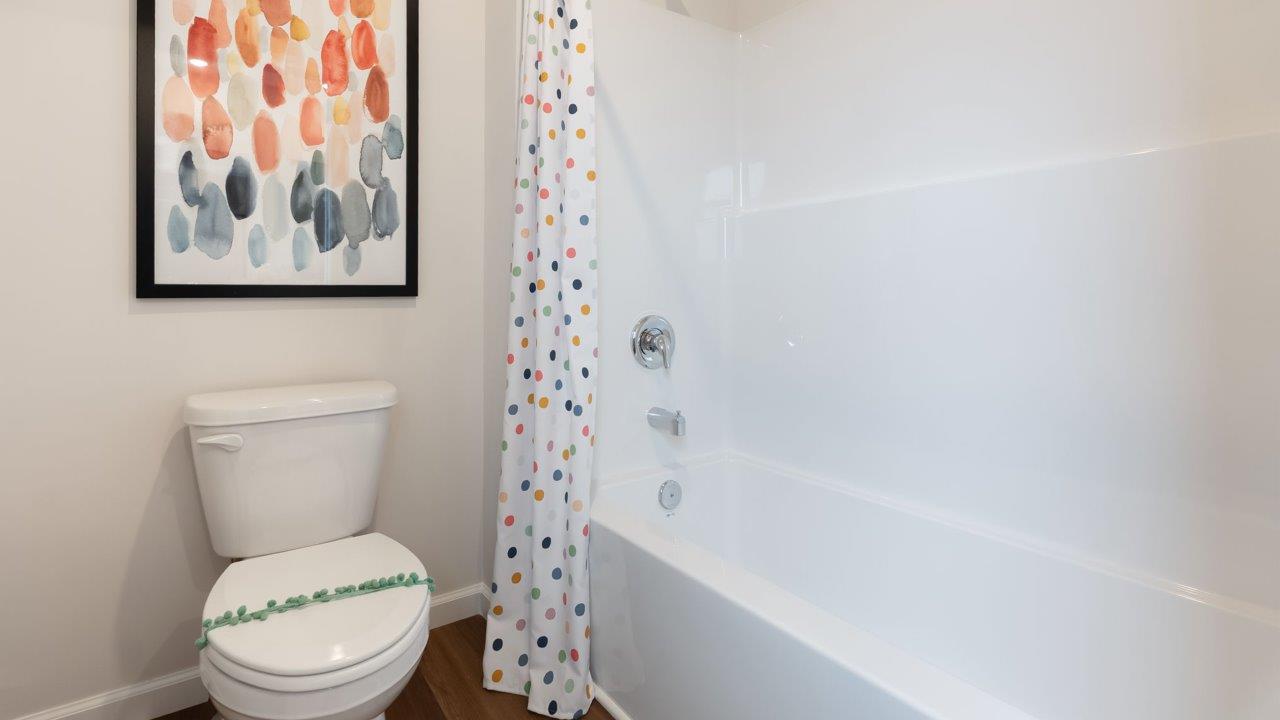farmstead at carroll creek henley model home full bathroom with dual sink vanity, tub shower, and private water room
