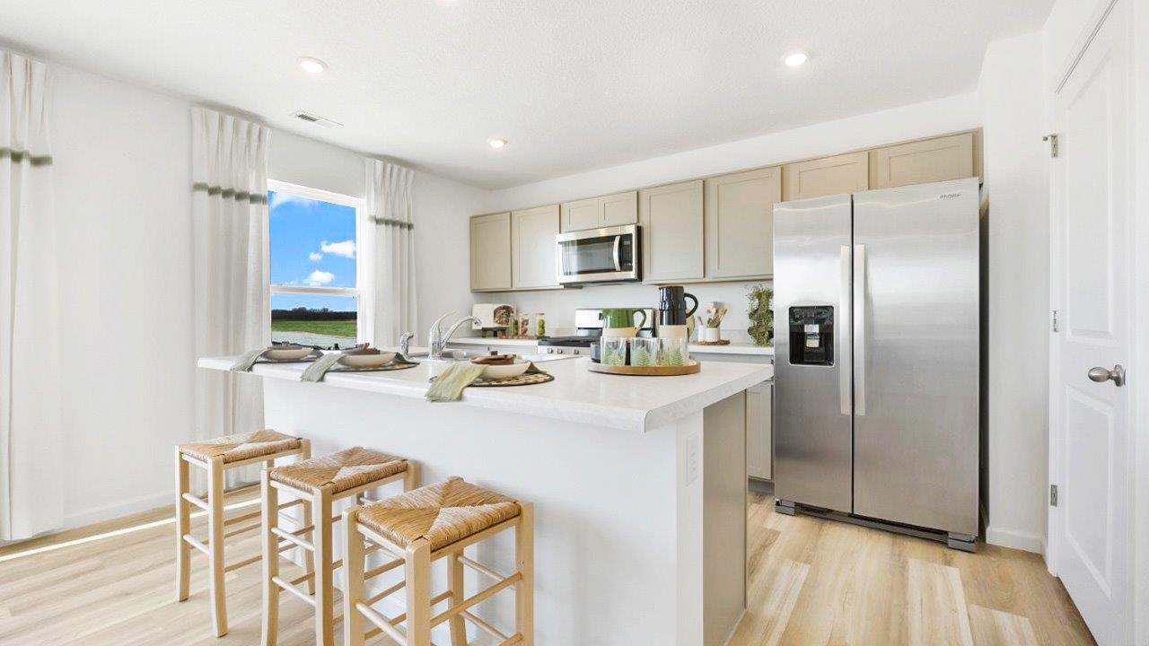 bellamy kitchen with grey cabinets, stainless steel appliances, center island with seating, and quartz counters