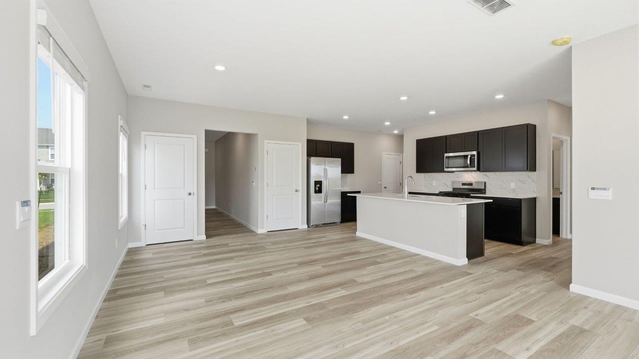 sonora elm open concept living room with sliding glass door to backyard and lvp flooring and kitchen overlooking living room