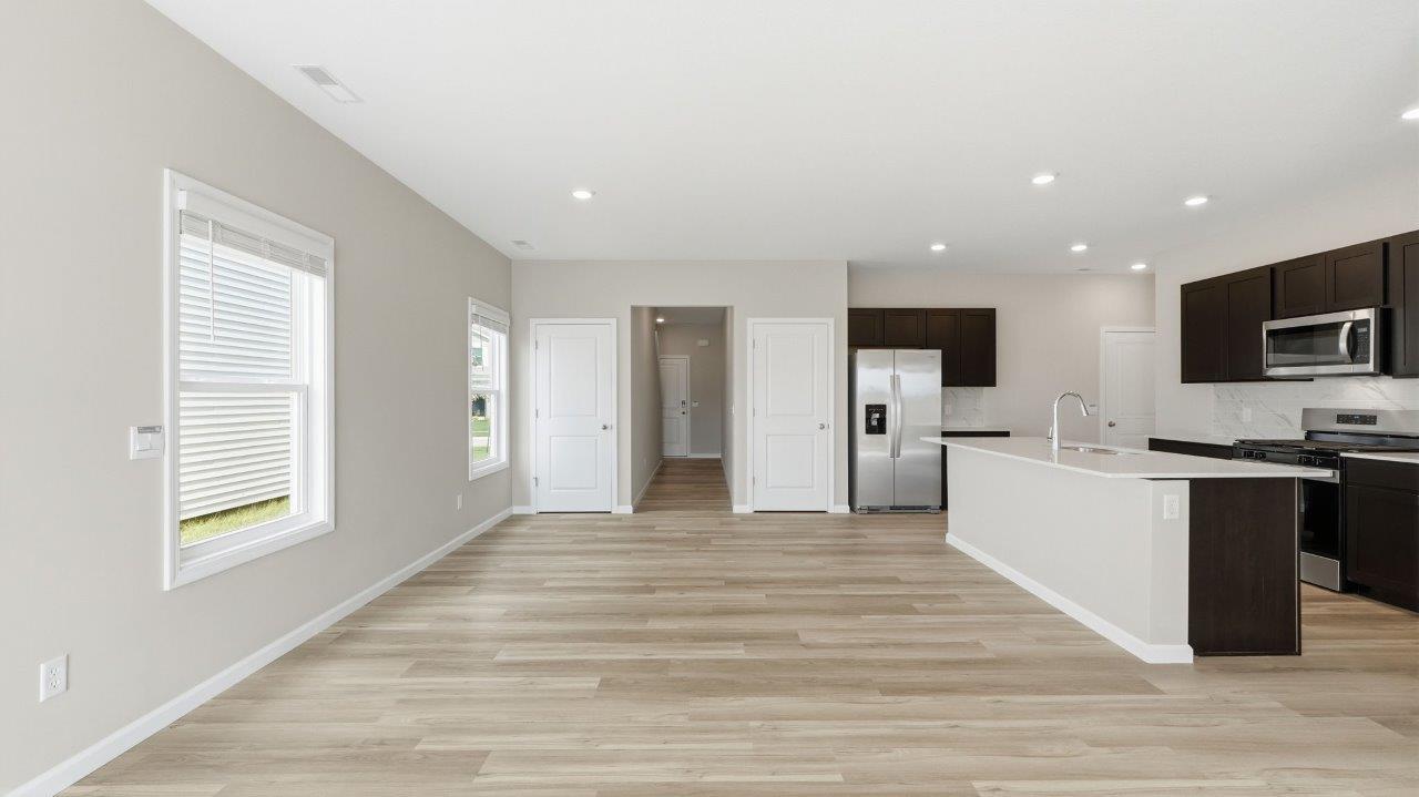 sonora elm open concept living room with sliding glass door to backyard and lvp flooring and kitchen overlooking living room