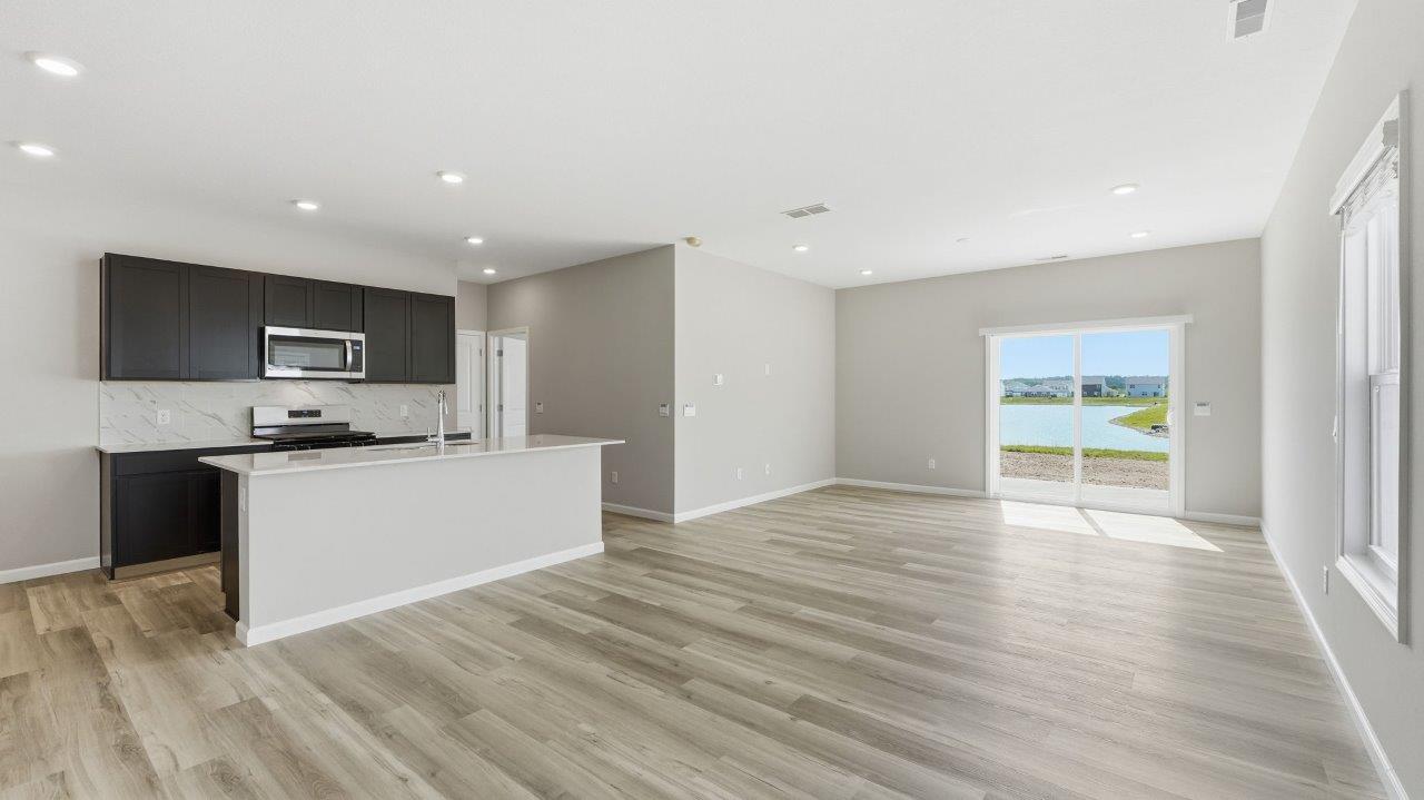 sonora elm open concept living room with sliding glass door to backyard and lvp flooring and kitchen overlooking living room