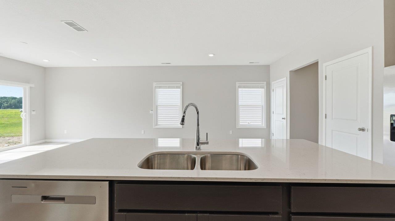 sonora elm kitchen with sarsaparilla cabinets, stainless steel appliances, center island with bar seating, quartz countertops, tile backsplash, and lvp flooring