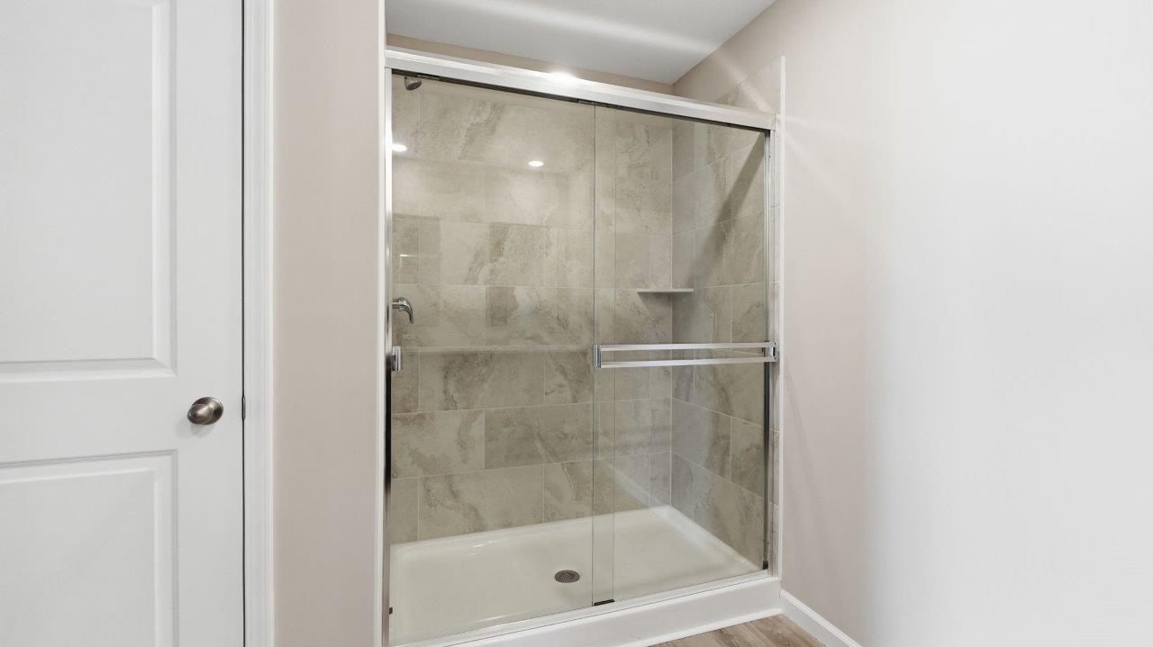 sonora elm primary ensuite bathroom with dual sink vanity and walk in ceramic tile shower with lvp flooring