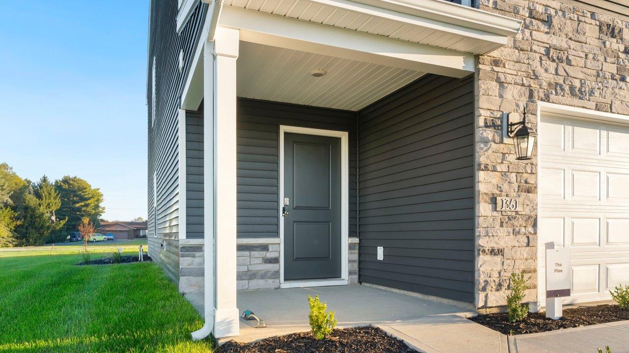 Greenbrier Pine Model Home - exterior with ironstone  vinyl siding, tuesdeo grey shutters, sterling shake, and weathered edge manistee stone