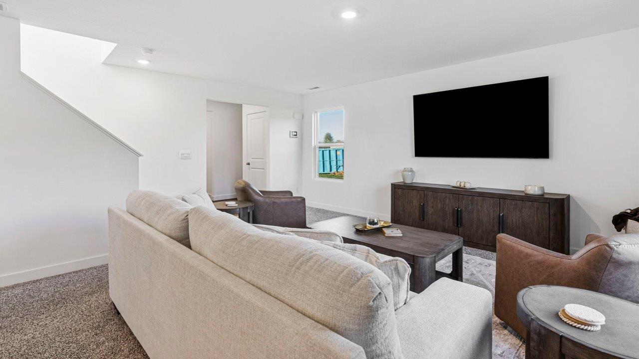 Greenbrier Pine Model Home - open layout living room with elk beige carpet flooring, white walls, and open to kitchen and casual dining spaces