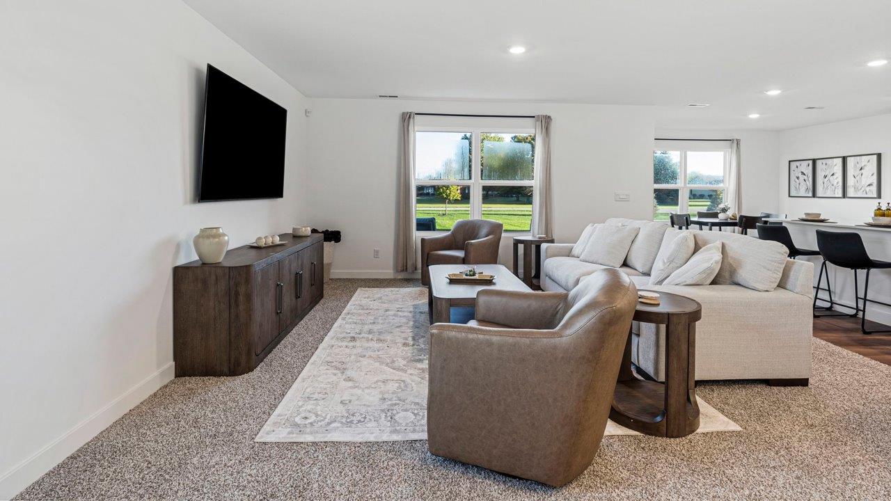Greenbrier Pine Model Home - open layout living room with elk beige carpet flooring, white walls, and open to kitchen and casual dining spaces