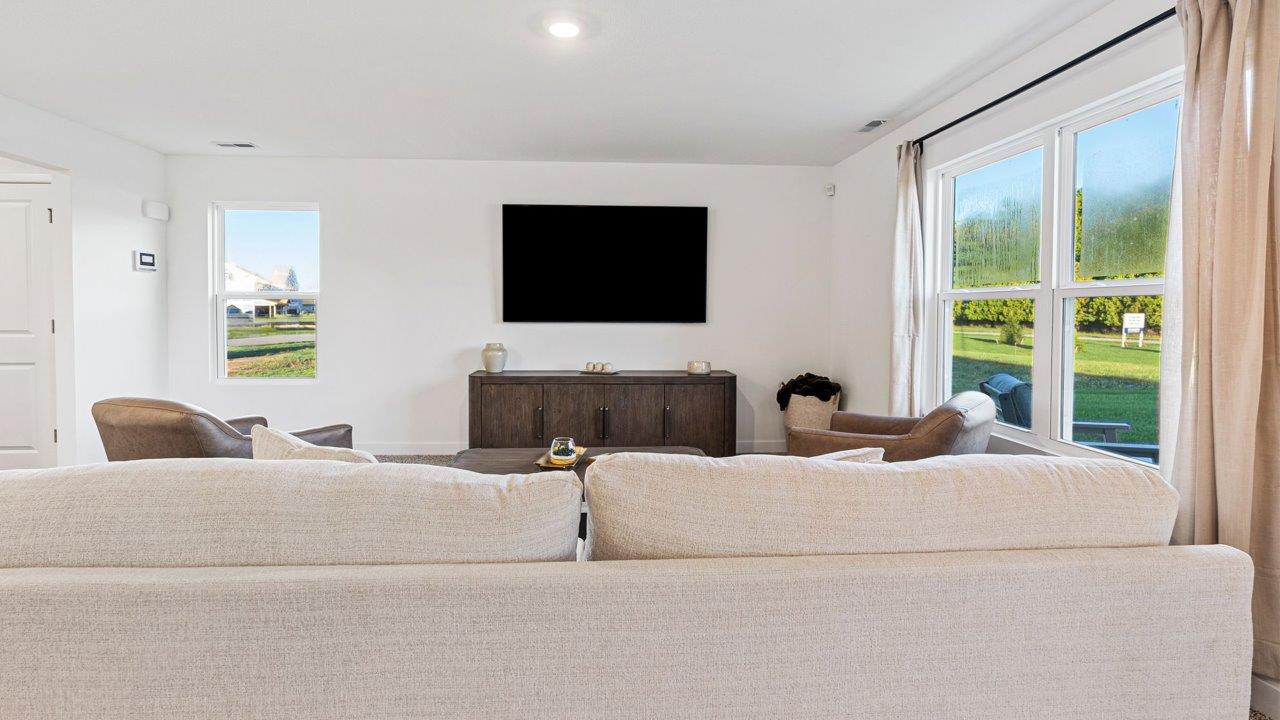 Greenbrier Pine Model Home - open layout living room with elk beige carpet flooring, white walls, and open to kitchen and casual dining spaces