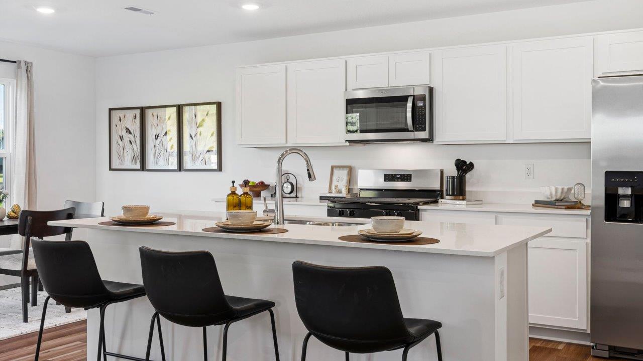 Greenbrier Pine Model Home - kitchen with white cabinets, quartz countertops, center island, pantry, and stainless steel appliances