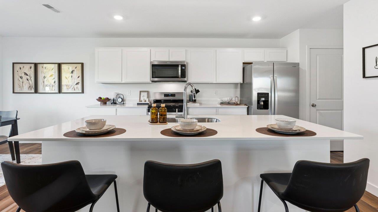 Greenbrier Pine Model Home - kitchen with white cabinets, quartz countertops, center island, pantry, and stainless steel appliances