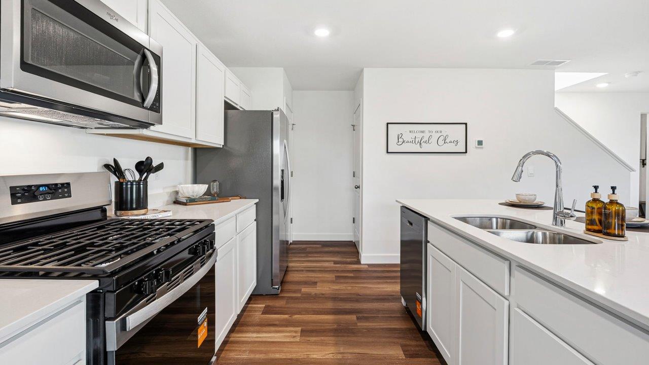 Greenbrier Pine Model Home - kitchen with white cabinets, quartz countertops, center island, pantry, and stainless steel appliances