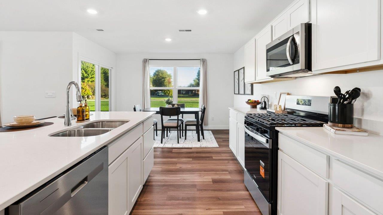Greenbrier Pine Model Home - kitchen with white cabinets, quartz countertops, center island, pantry, and stainless steel appliances