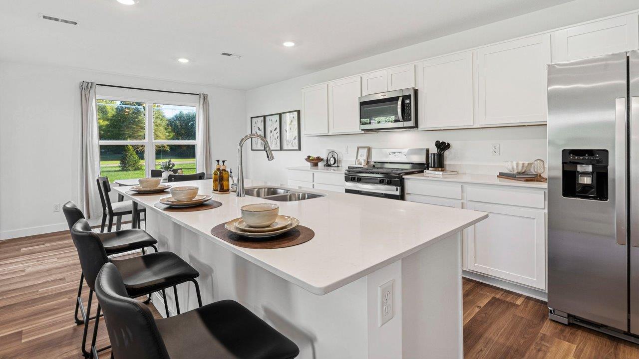 Greenbrier Pine Model Home - kitchen with white cabinets, quartz countertops, center island, pantry, and stainless steel appliances
