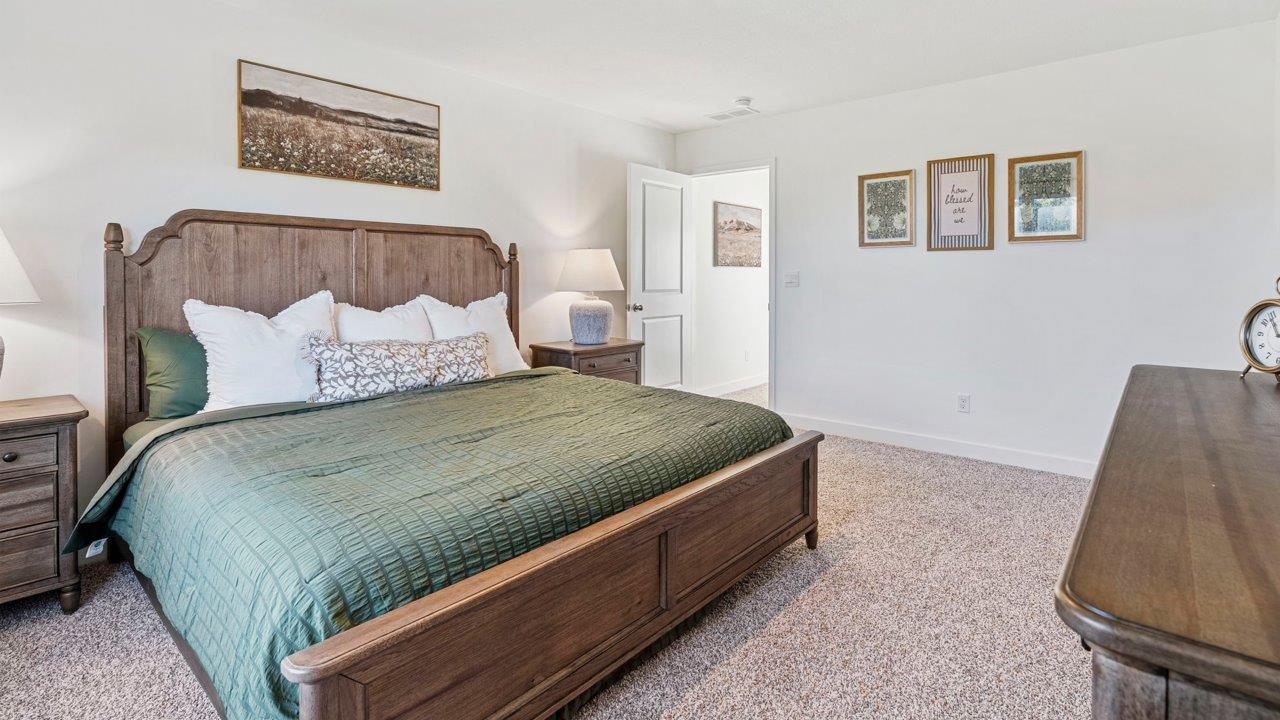 Greenbrier Pine Model Home - primary bedroom with carpet flooring, white walls, 2 windows, and ensuite bathroom and closet
