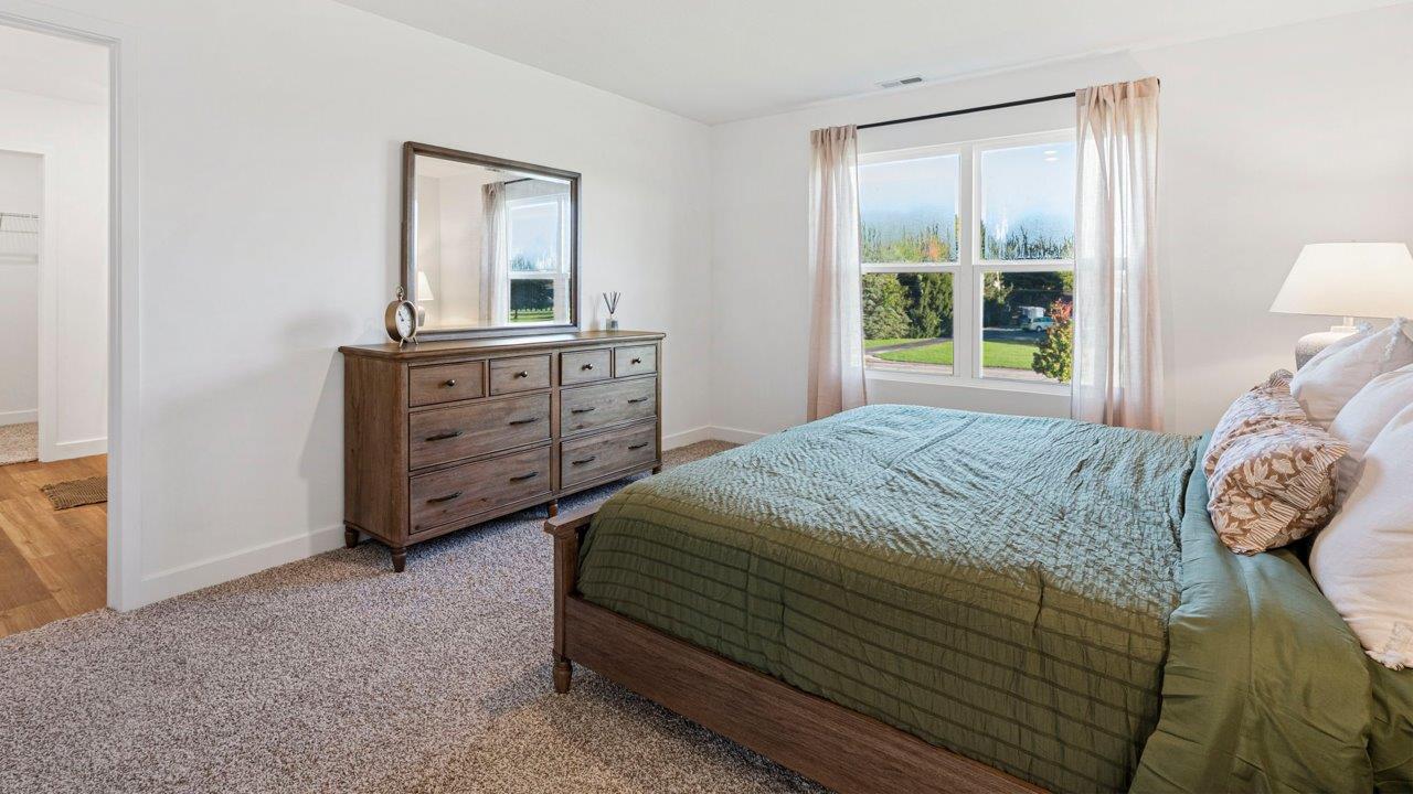 Greenbrier Pine Model Home - primary bedroom with carpet flooring, white walls, 2 windows, and ensuite bathroom and closet
